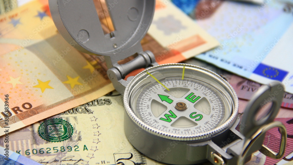 Small compass on international paper money. Where to move? Direction in economy to be found. Small compass on international paper money. Where to move? Direction in economy to be found.