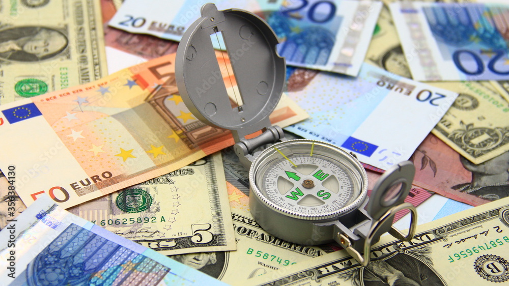Small compass on international paper money. Where to move? Direction in economy to be found. Small compass on international paper money. Where to move? Direction in economy to be found.