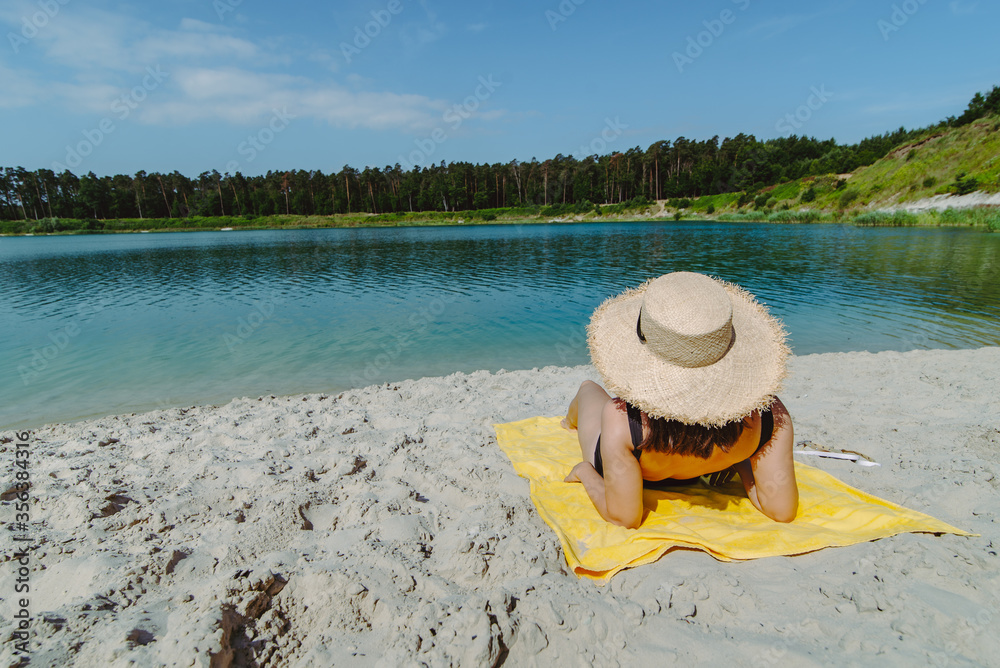 woman laying on yellow blanket sunbathing at sand beach woman laying on yellow blanket sunbathing at sand beach