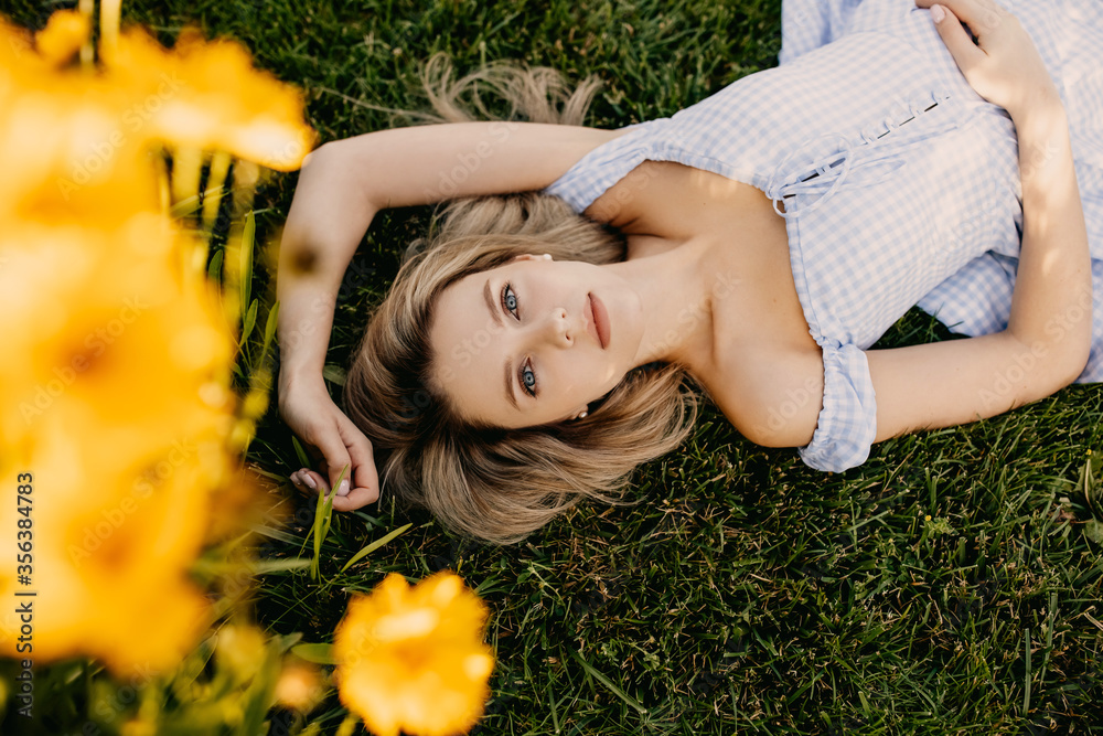 Young woman with long blonde hair, lying on grass with blue eyes, looking to camera. Young woman with long blonde hair, lying on grass with blue eyes, looking to camera.