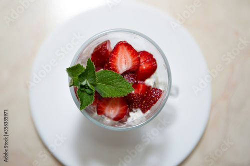 Sweet strawberry with mint in clear glass and white plate
