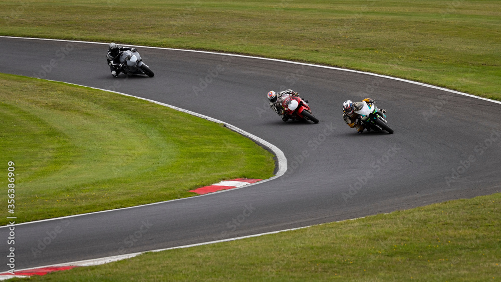 A panning shot of multiple racing bikes cornering on a track
