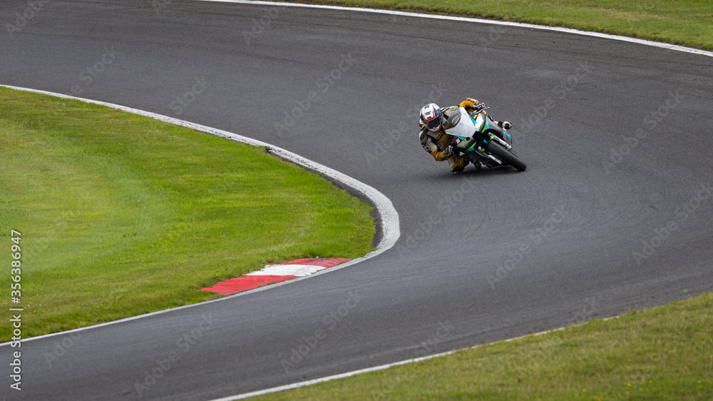 A panning shot of a black racing bike cornering on a track
