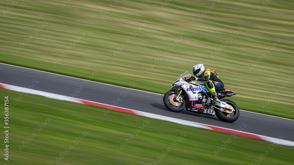 A panning shot of a white racing bike cornering on a track