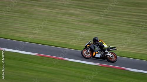 Fotografie, Obraz A panning shot of a black racing bike cornering on a track