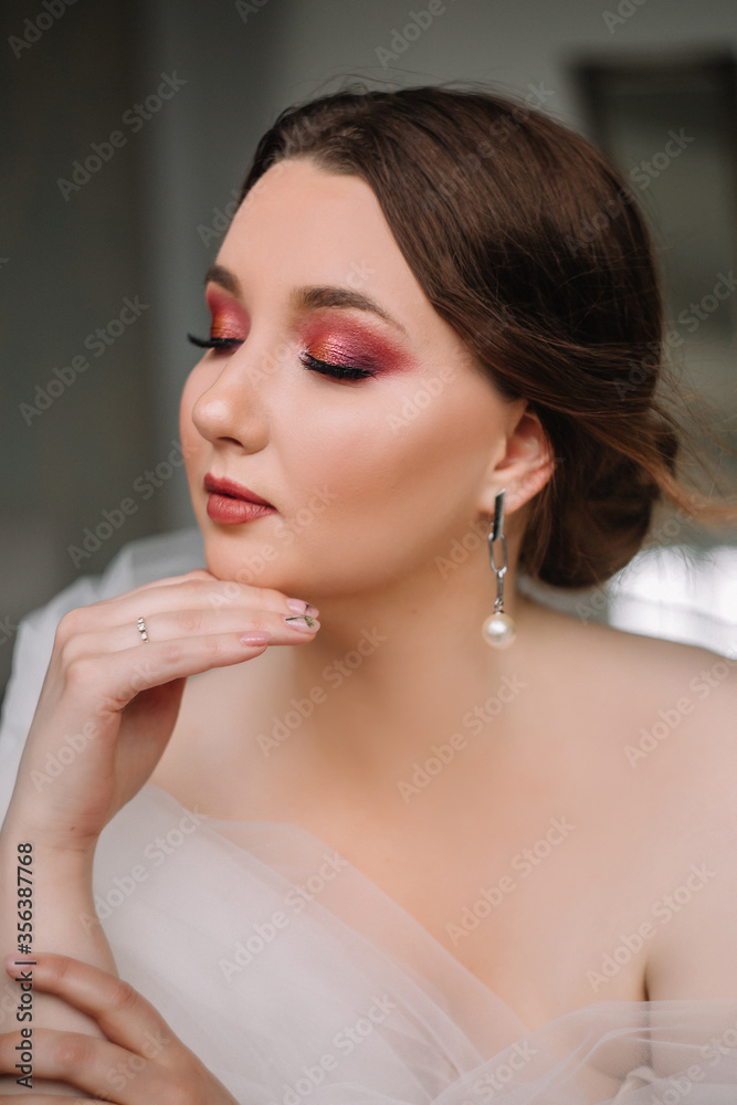 Beautiful model girl bride with bright makeup gently looks at the camera. Portrait