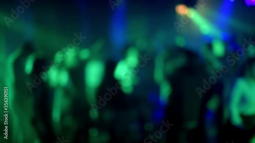 blurred silhouettes of a crowd of people dancing on the dance floor in a nightclub photo