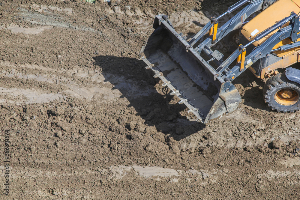 the bucket of a small tractor lies on the road. The concept of repair, house building. bucket after working in the sand the bucket of a small tractor lies on the road. The concept of repair, house building. bucket after working in the sand