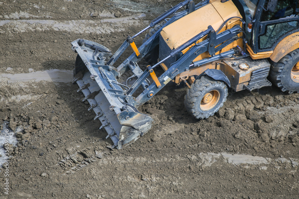 the bucket of a small tractor lies on the road. The concept of repair, house building. bucket after working in the sand the bucket of a small tractor lies on the road. The concept of repair, house building. bucket after working in the sand