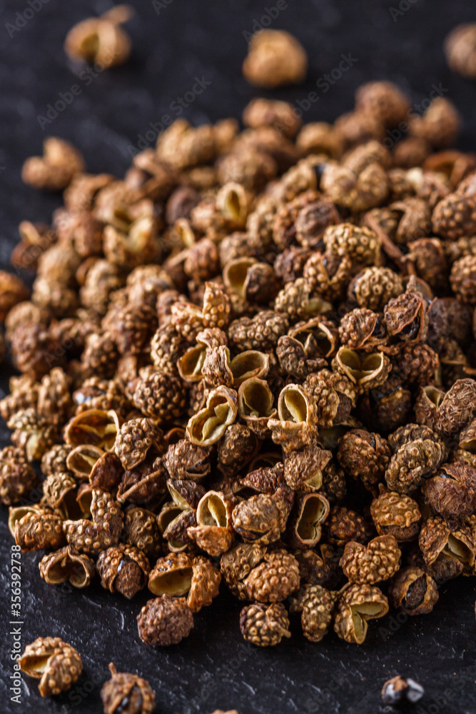 Obraz premium Sichuan pepper on a dark stone background