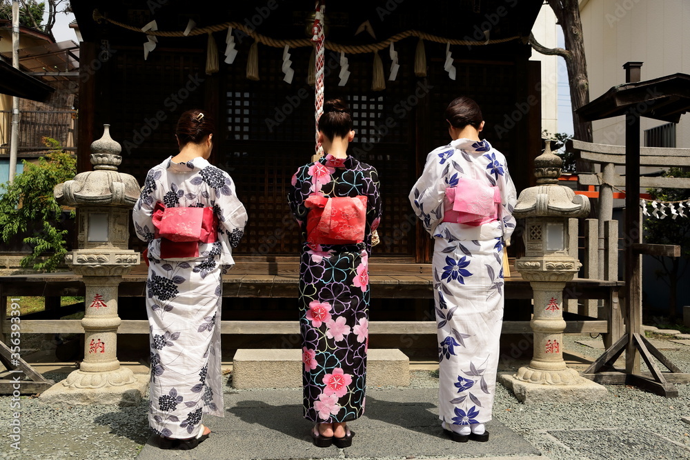 日本の神社でお参りする美しい浴衣の女性