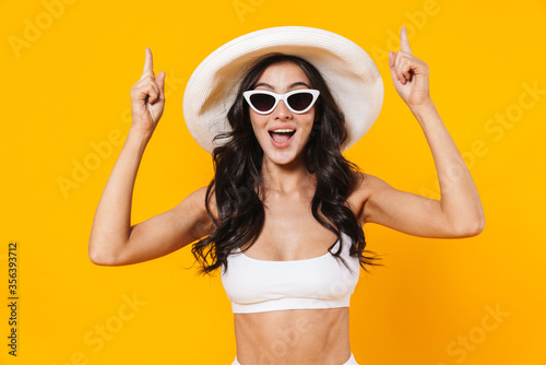 Image of stylish excited woman smiling and pointing fingers upward