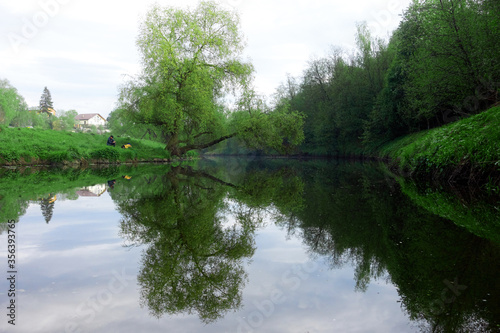 Reflection of green trees and banks in a calm river in the summer. River rafting in summer. Packrafting in wilderness. photo