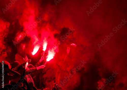 Football fans lit up the lights, flares and smoke bombs. Protest concept. Red smoke and torches