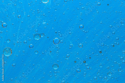 Abstract blue background with oil drops and waves on water surface
