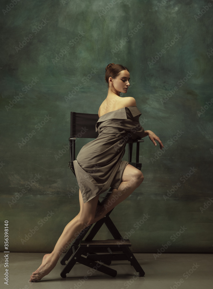Beautiful portrait, elegance. Graceful classic ballerina dancing, posing isolated on dark studio background. Stylish trench coat. Grace, movement, action and motion concept. Looks weightless, flexible