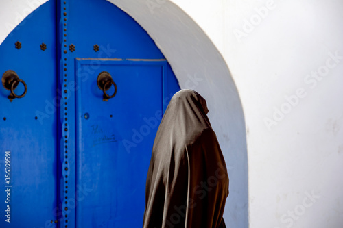 Foto Tunisia. Sidi Bou Said. Woman in chador walking in the Medina