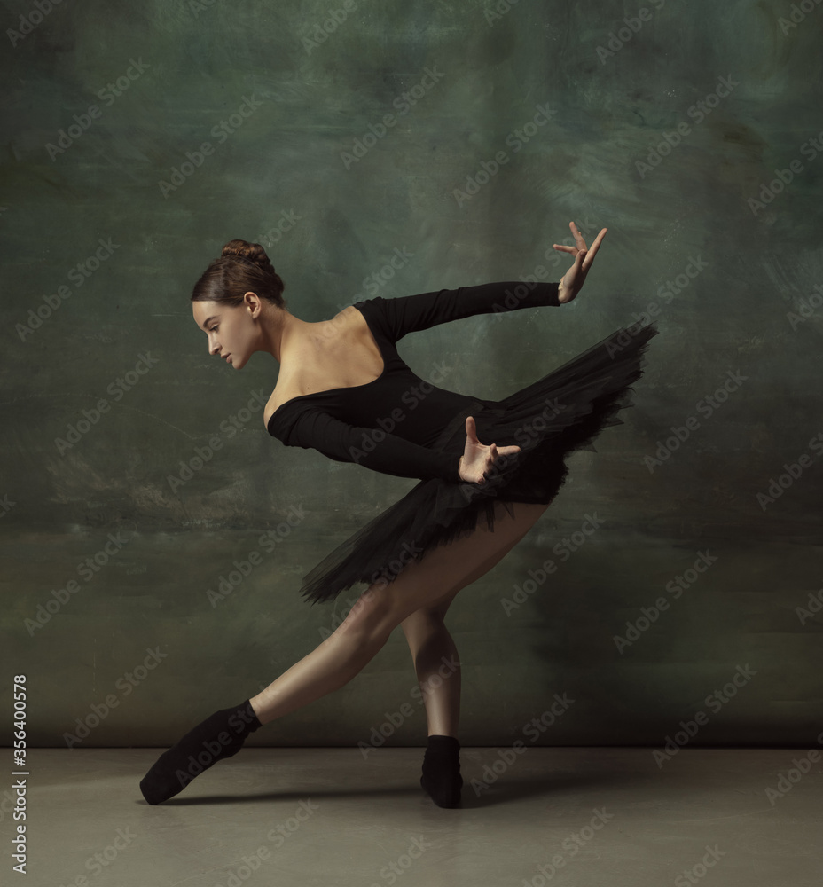Mystic mood. Graceful classic ballerina dancing, posing isolated on dark studio background. Elegance black tutu. Grace, movement, action and motion concept. Looks weightless, flexible. Fashionable.