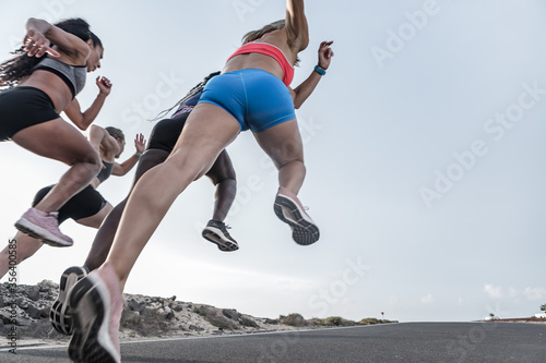 Unrecognizable diverse friends sprinting on road