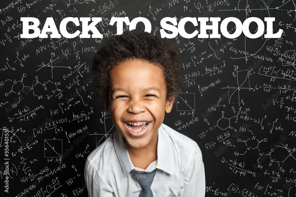Happy black child boy student laughing on chalkboard background. Back to school concept Happy black child boy student laughing on chalkboard background. Back to school concept