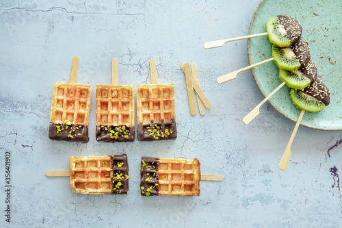 Kiwi am Stiel und Waffeln mit Kardamom-Schokolade, Pistazien und Sesam photo
