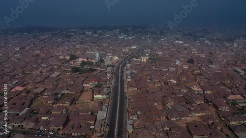 Aerial view of the main highway through the center of Ogdomosho, Nigeria at dusk with red roofs and drit below and smog on the horizon photo