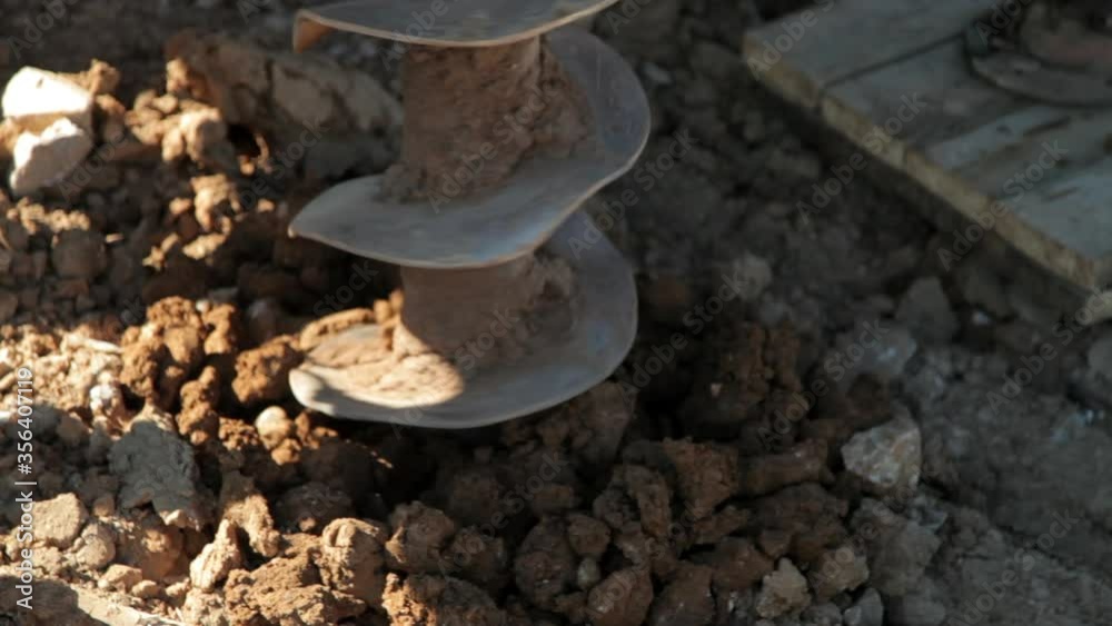 Water well drilling rig.Drill is digging a hole.Brown, clay soil.Close-up. Water well drilling rig.Drill is digging a hole.Brown, clay soil.Close-up.