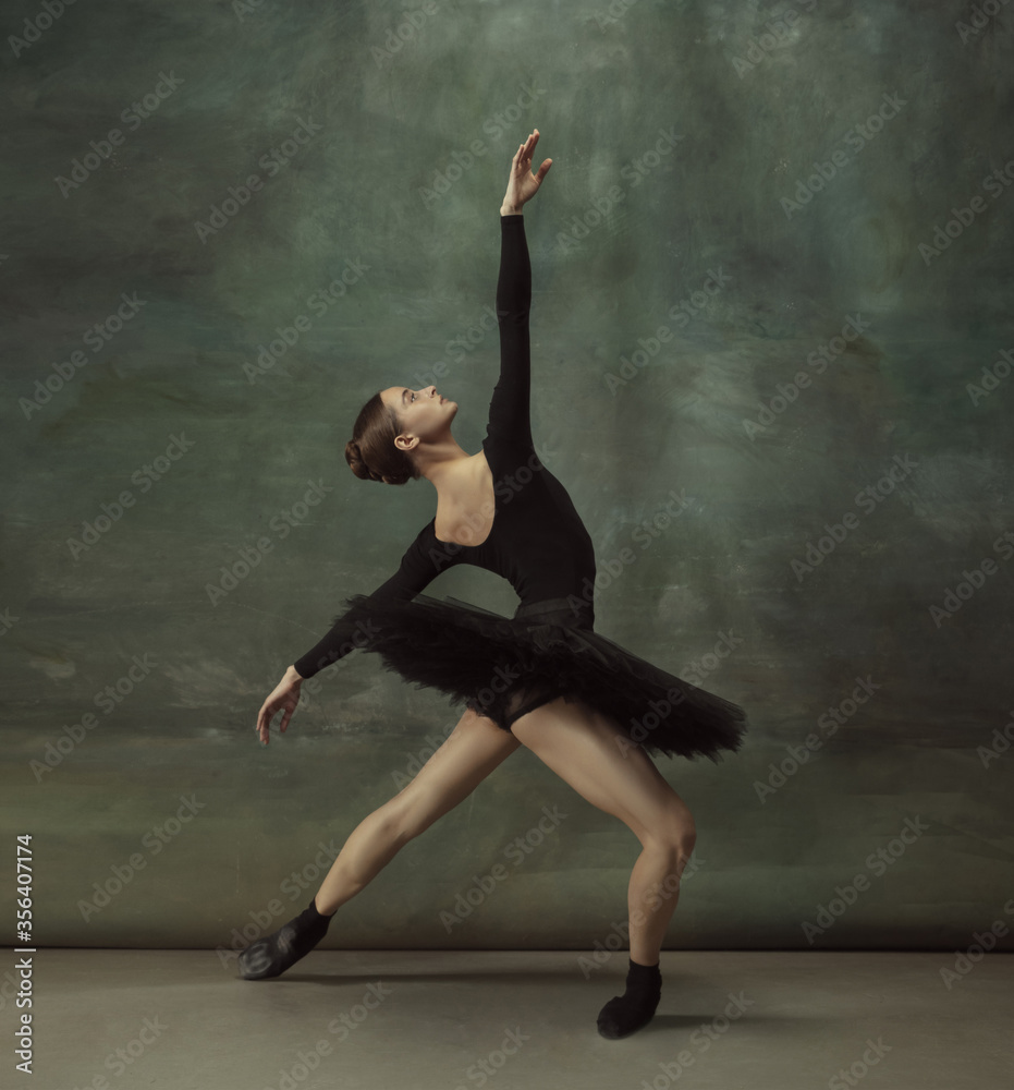 Dancing night. Graceful classic ballerina dancing, posing isolated on dark studio background. Elegance black tutu. Grace, movement, action and motion concept. Looks weightless, flexible. Fashionable. Dancing night. Graceful classic ballerina dancing, posing isolated on dark studio background. Elegance black tutu. Grace, movement, action and motion concept. Looks weightless, flexible. Fashionable.
