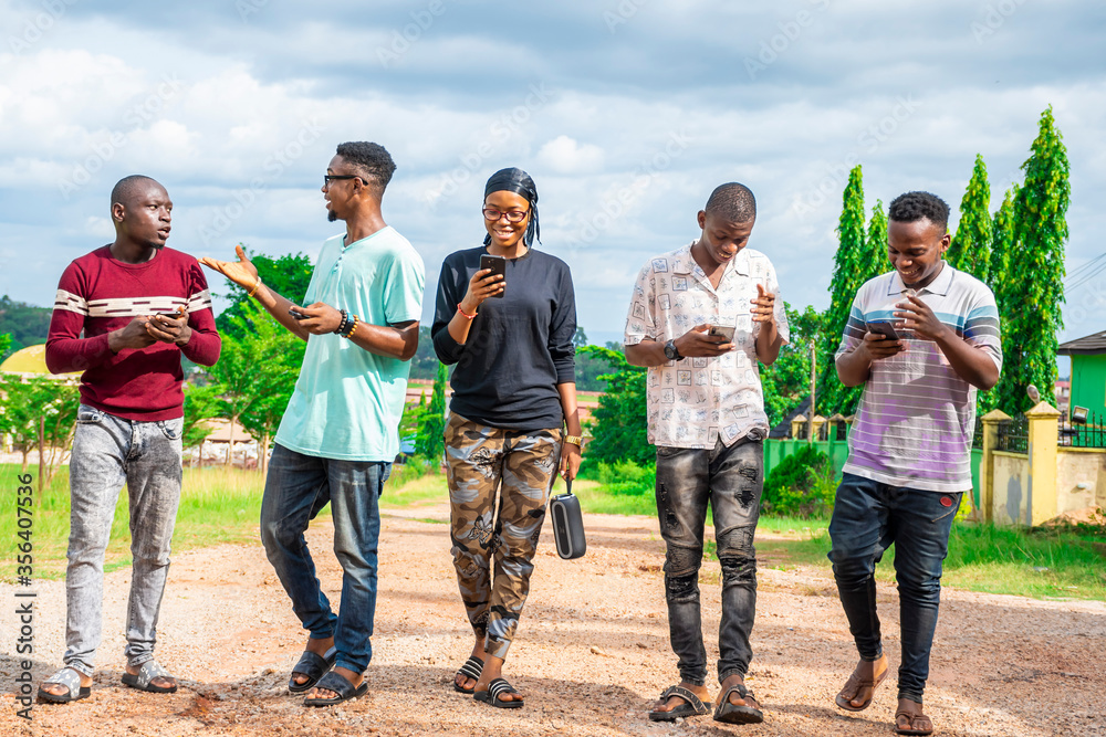 group of friends, walking together, having fun, using their mobile phones group of friends, walking together, having fun, using their mobile phones