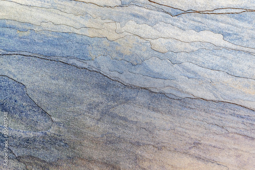 The texture of a multilayer stone is light blue. Background of a stone imitating waves. © Elena