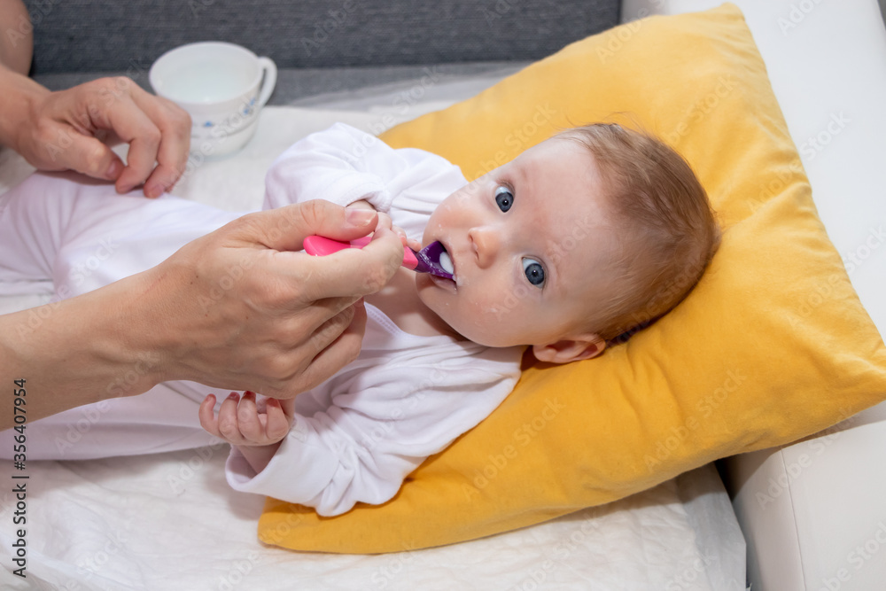 Little baby girl eating rice soup with spoon. Happy little cute daughter with blue eyes. The baby girl is four months old. Little baby girl eating rice soup with spoon. Happy little cute daughter with blue eyes. The baby girl is four months old.
