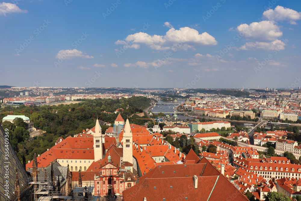 view on the roofs of Prague,  the capital of Czech Republic with cloudy blue sky and great view on the Moldova in the center of this picture