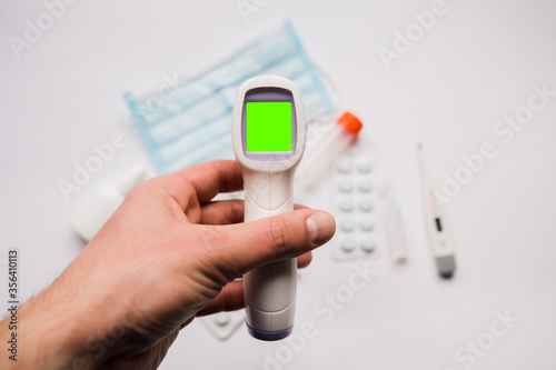 electronic thermometer in hand with medical mask