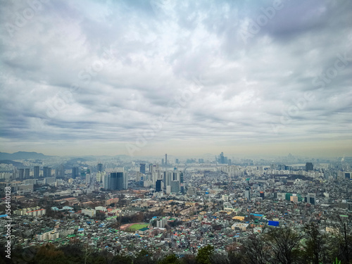 High angle view of part of capital city of Seoul from high ground at namsan Seoul South Korea. Visible noise and soft focus due to foggy and cloudy morning. Cloudy blue sky at background. © MailHamdi
