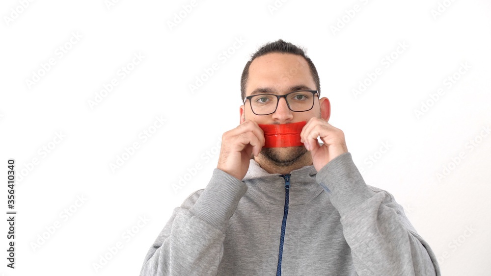 Caucasian man seals his mouth with tape in protest. Portrait of a man with tape on mouth over white background. Prohibition of freedom of speech. Silence Caucasian man seals his mouth with tape in protest. Portrait of a man with tape on mouth over white background. Prohibition of freedom of speech. Silence