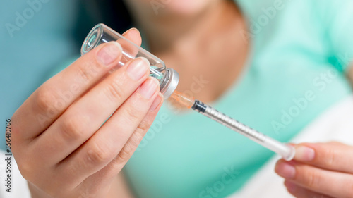 Closeup image of woman filling syringe with insulin