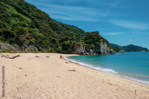 Couple on the beach in front of a cliff at Abel Tasman National Park. Anapai Bay.