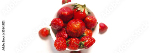 Fresh red strawberries in a bowl on white background close up.