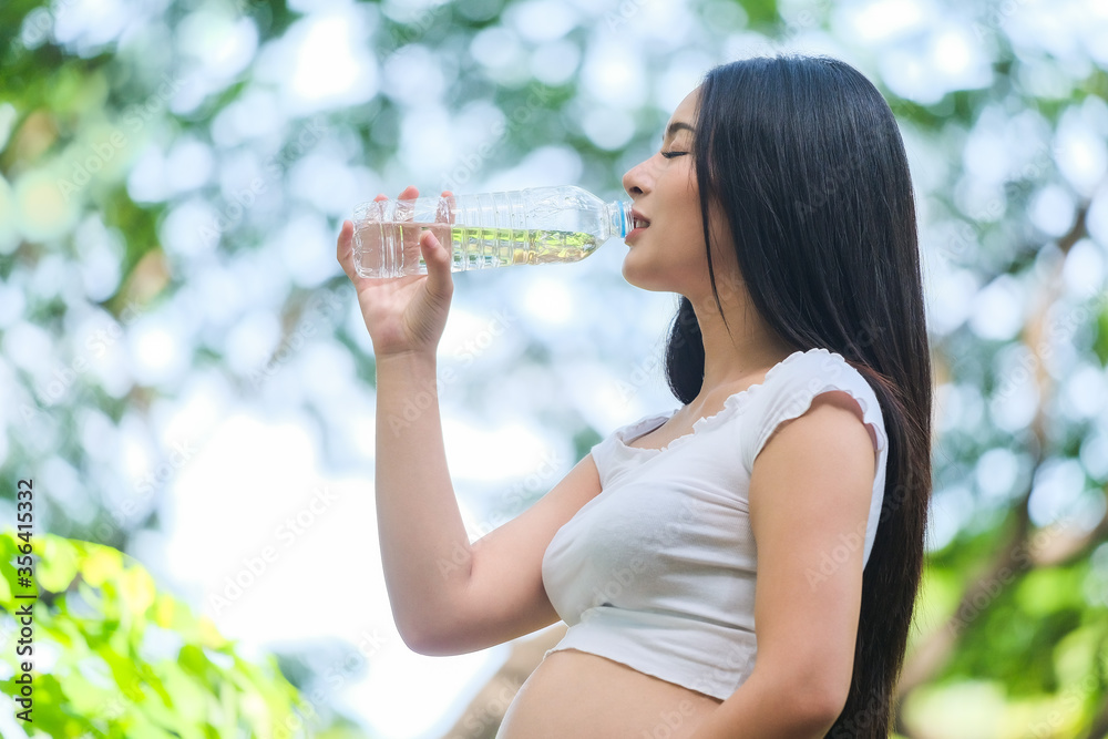 Pregnant women drink cold water after exercising in the park in fresh air. Pregnant women drink cold water after exercising in the park in fresh air.