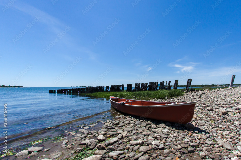 Red canoe on rocky bech with beautiful blue sky