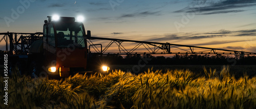 Machine for spraying pesticides and herbicides on a field at night. photo
