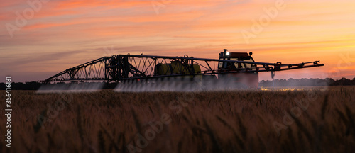 фотографія Machine for spraying pesticides and herbicides on a field at night