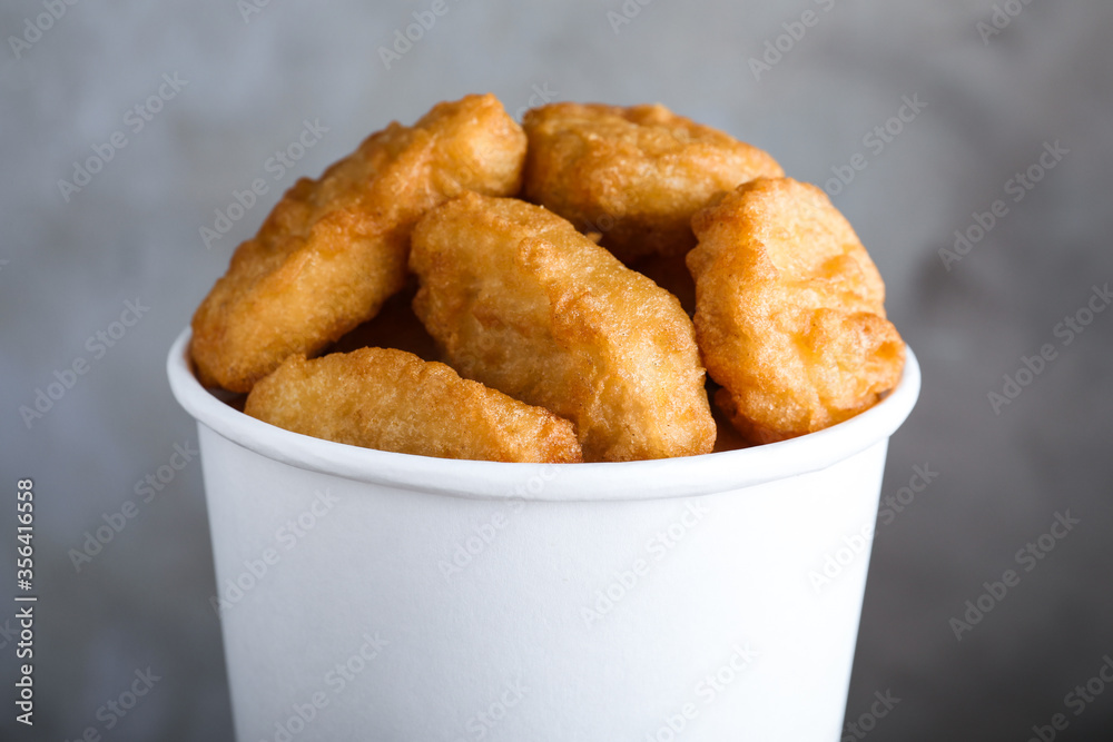 Bucket with delicious chicken nuggets on grey background, closeup Bucket with delicious chicken nuggets on grey background, closeup