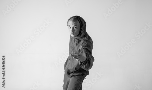 A man hip hop dancer or bboy freezes in one pose on a white background. Bboy doing stylish stunts.