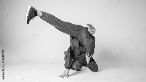 A man hip hop dancer or bboy freezes in one pose on a white background. Bboy doing stylish stunts. photo