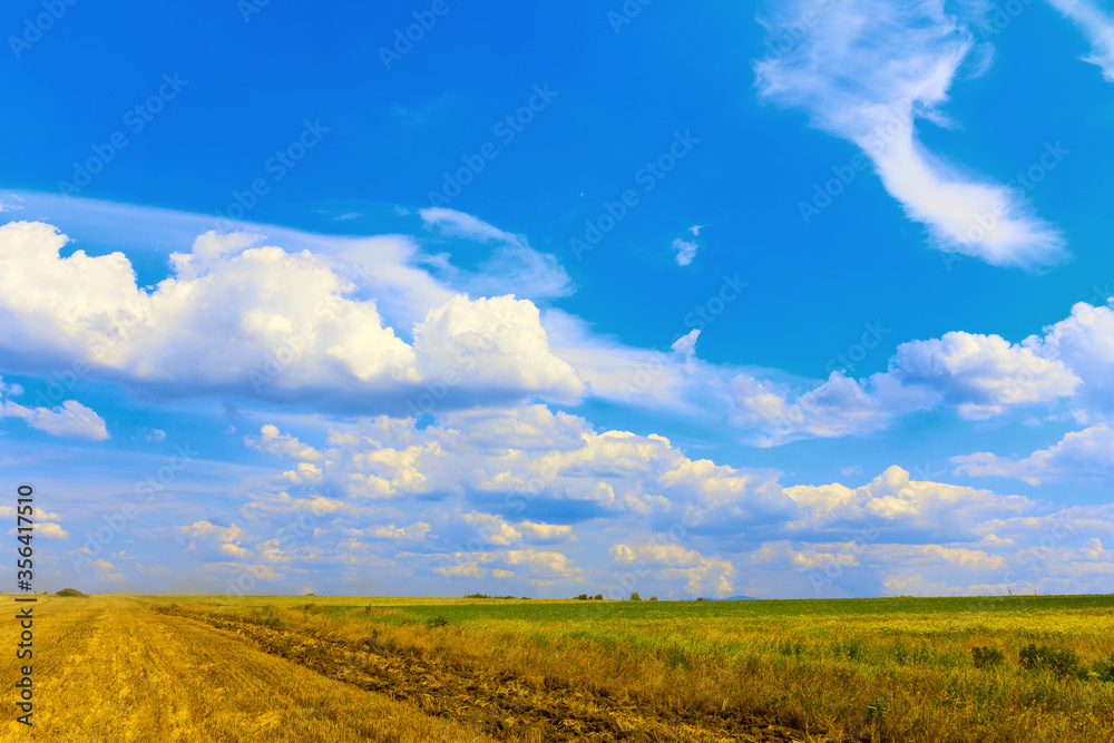 Beautiful beautiful cloudy sky over a mown field and meadow