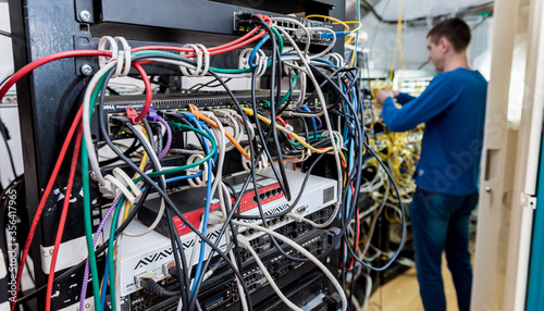 Network engineer working in server room. Connecting network cables to switches