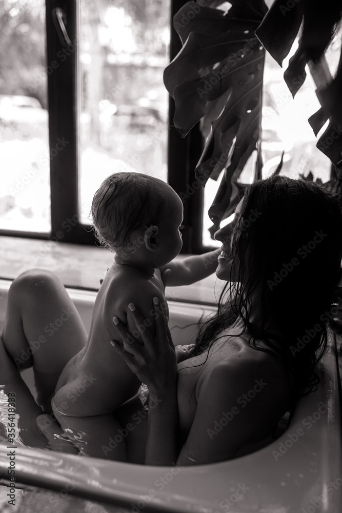 Mother bathes in bathtub and plays with her baby. Mother bathes in bathtub and plays with her baby.