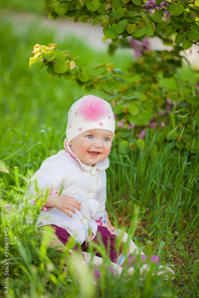 Beautiful happy baby girl sitting on green grass in the park. Beautiful happy baby girl sitting on green grass in the park.