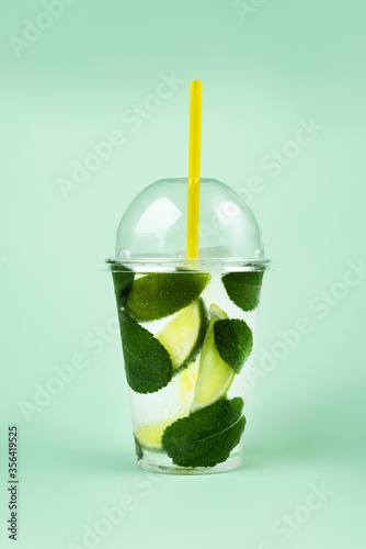 Lemonade to go cup with mint and lime on green background, isolated